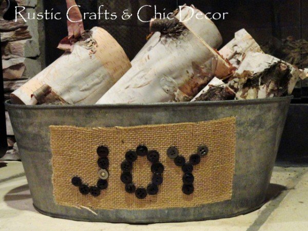 Tin bucket with a button and burlap label filled with birch logs.