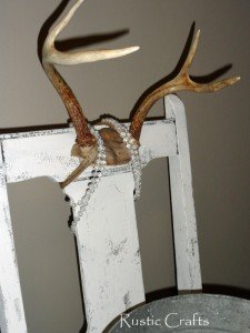 rustic chic chair with antlers Decorating with antlers by adhering deer antler to the top middle of a distressed white chair. Antlers are then draped with faux pearls. Tin bucket is placed in seatless chair for magazine storage.